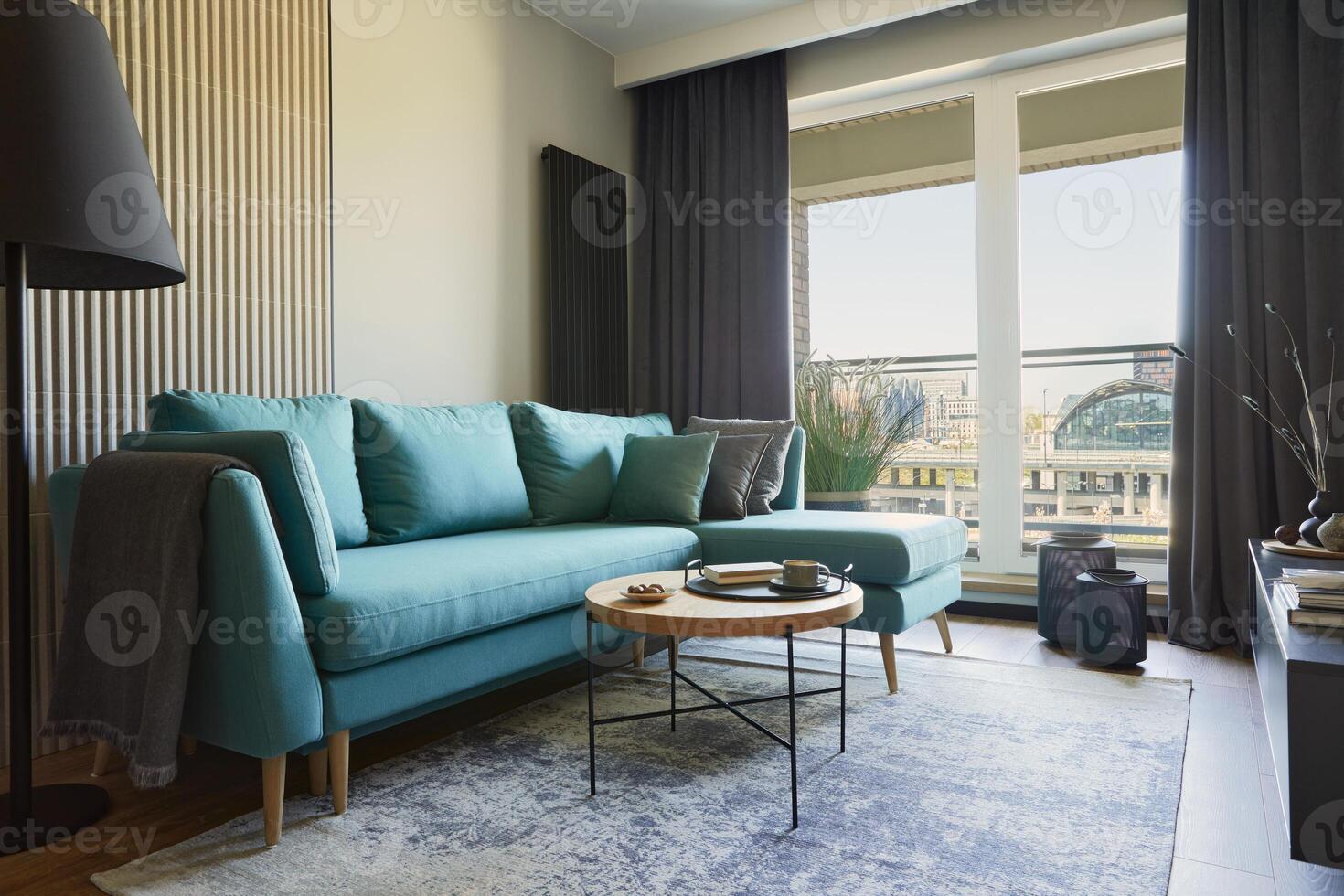 Stylish composition of modern living room interior in small apartment. Eucalyptus sofa, wooden coffee table and personal accessories. Panorama windows with a big city view on. Creative wall. Template. photo