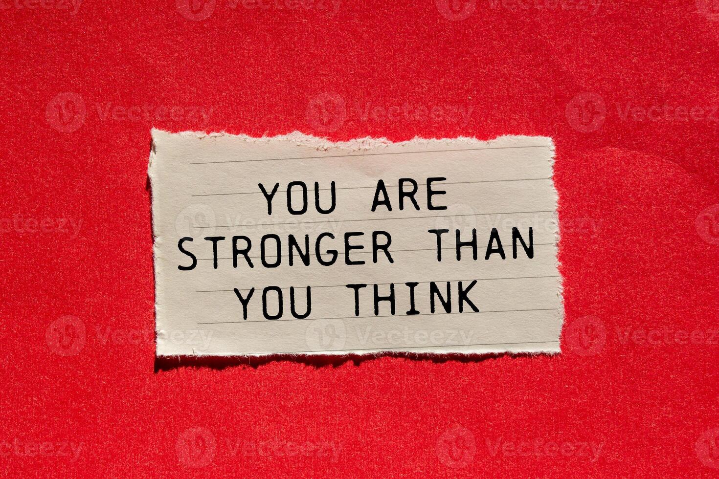 You are stronger than you think message written on ripped torn paper piece on red background. Conceptual you are stronger than you think symbol. Copy space. photo