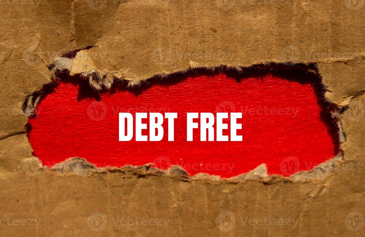 Debt free message written on torn cardboard paper with red background. Conceptual debt free symbol. Copy space. photo