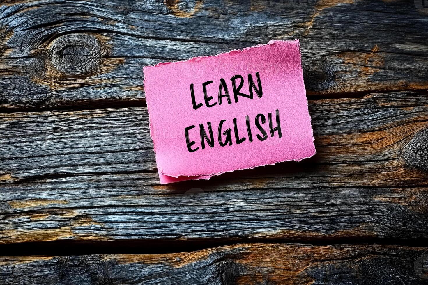 Learn english written on a pink sticky note on a wooden background photo