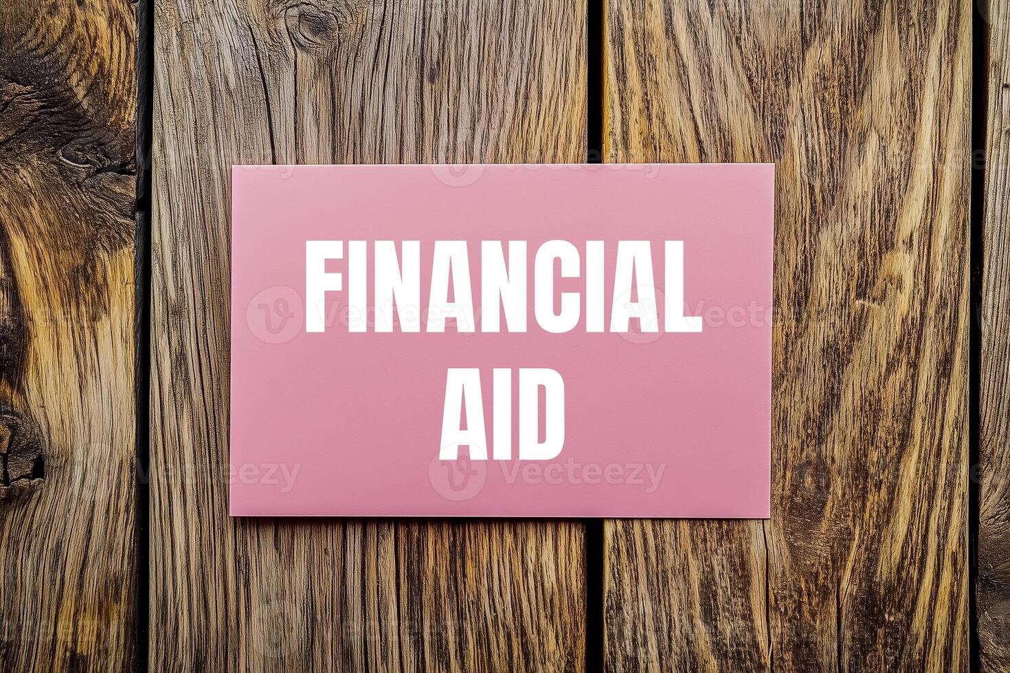 Financial aid message written on pink card with wooden background. Conceptual financial aid symbol. Copy space. photo