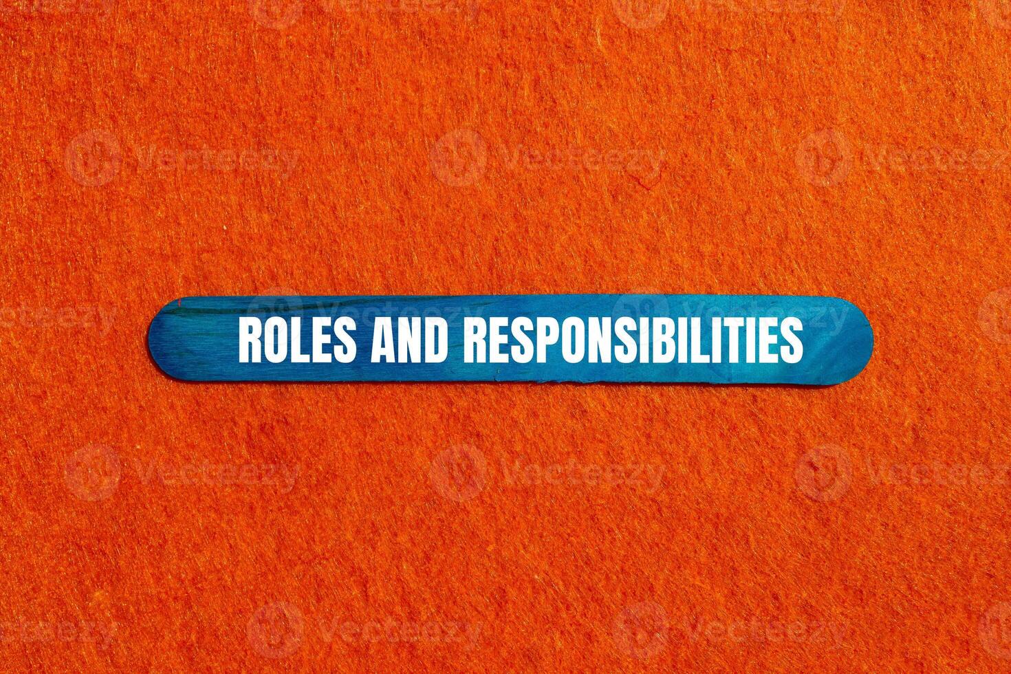 Roles and responsibilities message written on blue wooden stick on orange background. Conceptual roles and responsibilities symbol. Copy space. photo