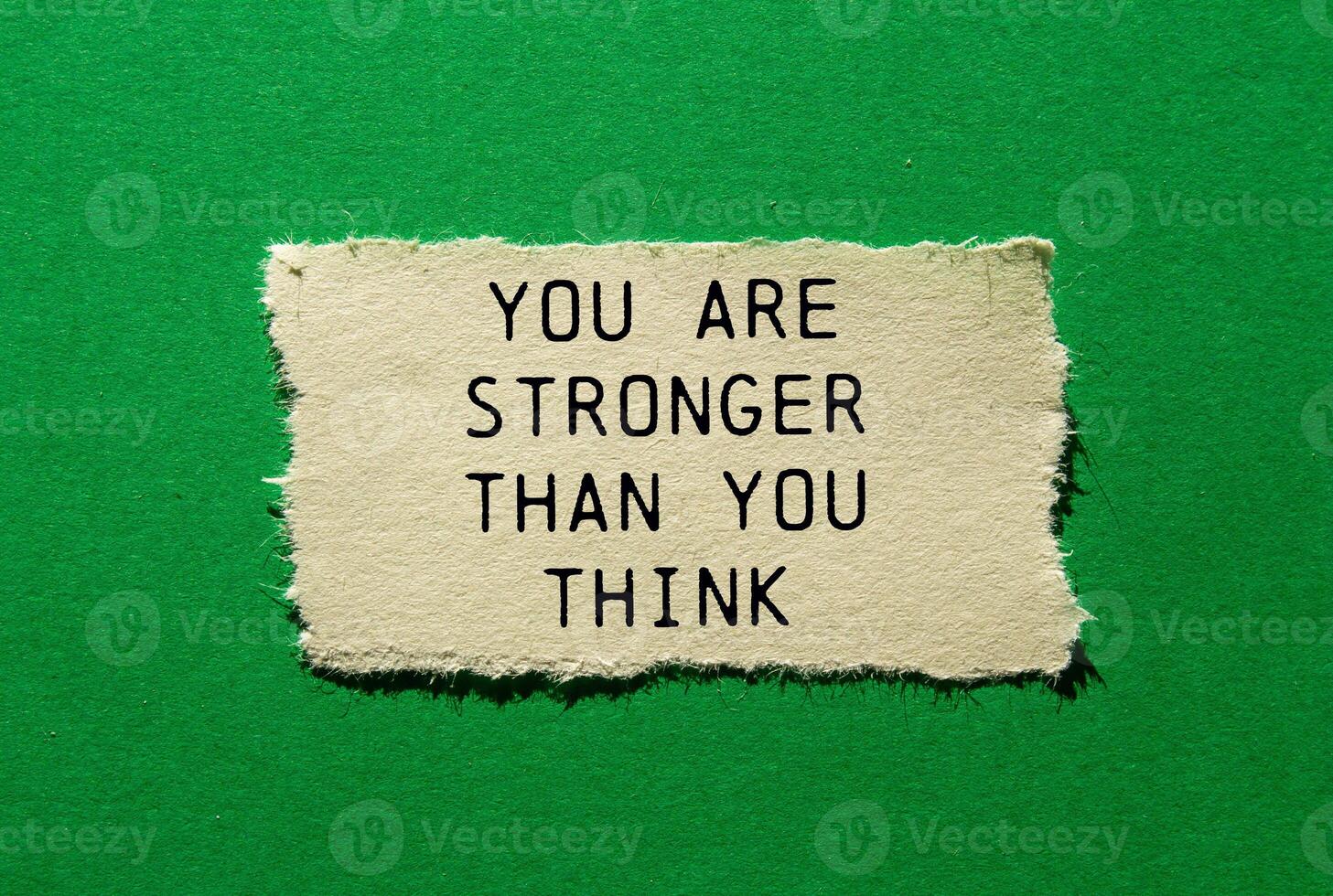 You are stronger than you think message written on ripped torn paper piece on green background. Conceptual you are stronger than you think symbol. Copy space. photo