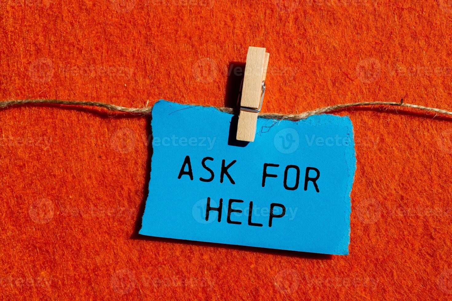 Ask for help message written on ripped blue torn paper piece on orange background. Conceptual ask for help symbol. Copy space. photo