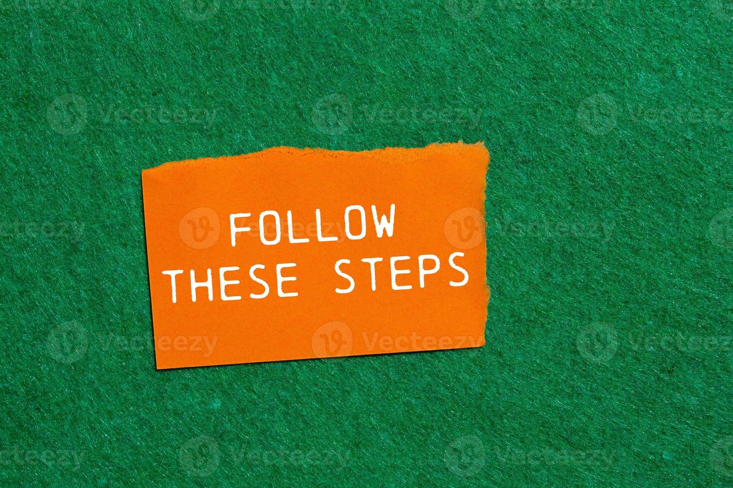 Follow these steps message written on ripped orange torn paper piece on green background. Conceptual follow these steps symbol. Copy space. photo