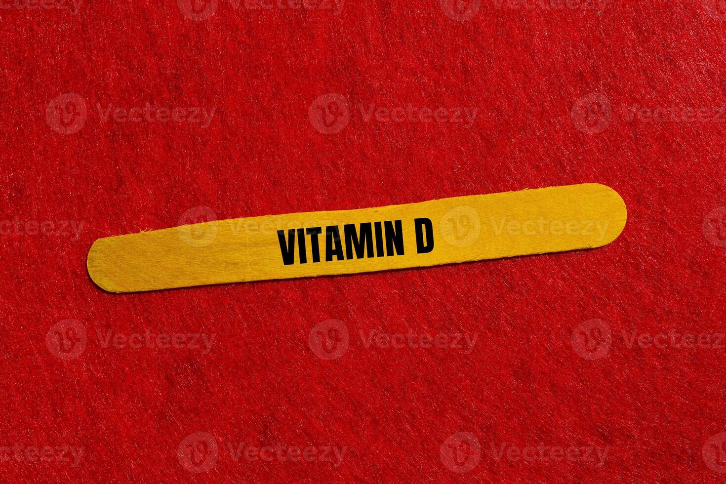 Vitamin d message written on yellow wooden stick with red background. Conceptual vitamin d symbol. Copy space. photo
