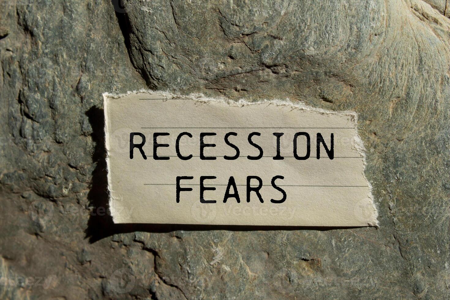 Recession fears message written on ripped torn paper piece on stone background. Conceptual recession fears symbol. Copy space. photo