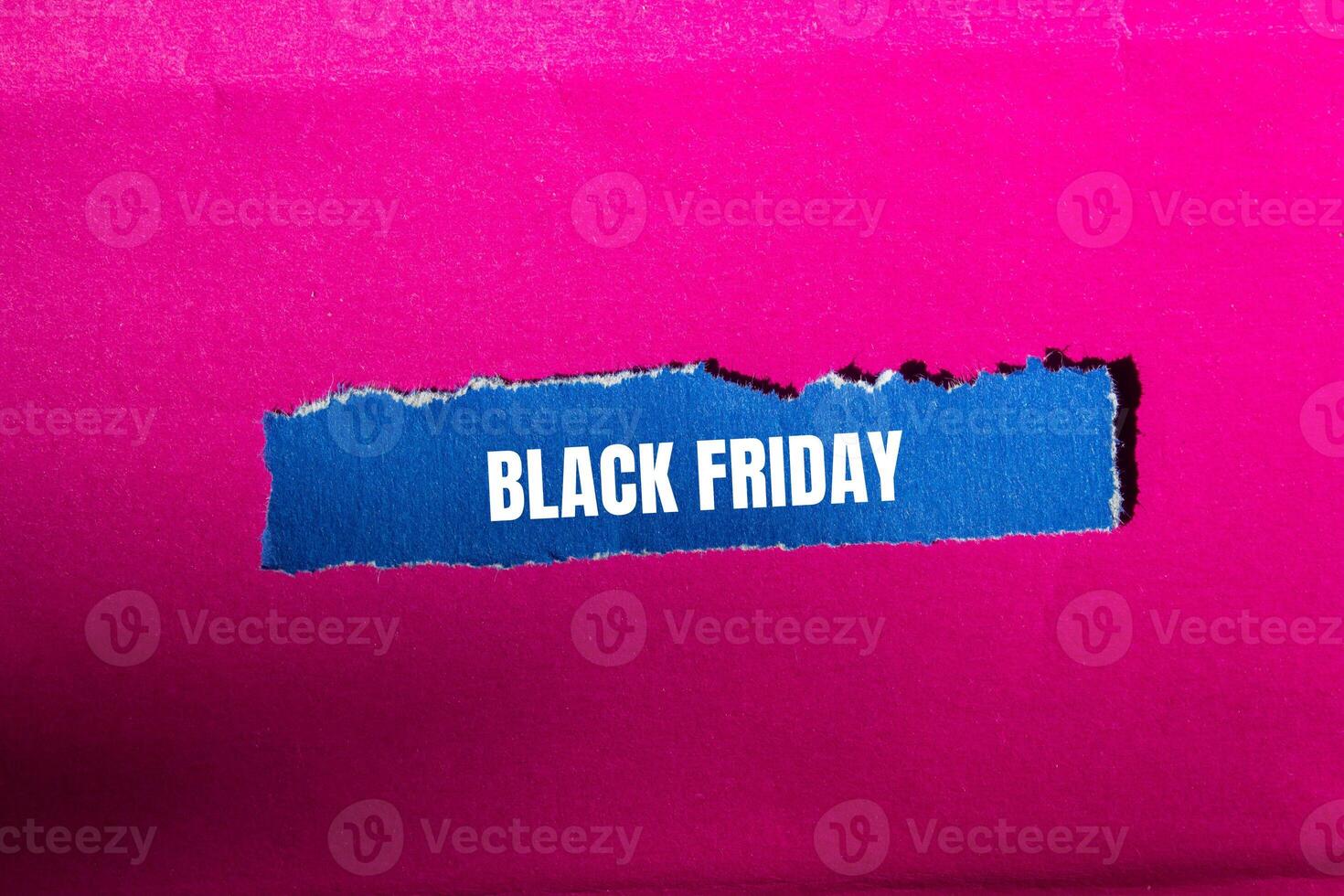 Black friday message written on ripped torn blue paper piece with pink background. Conceptual black friday symbol. Copy space. photo