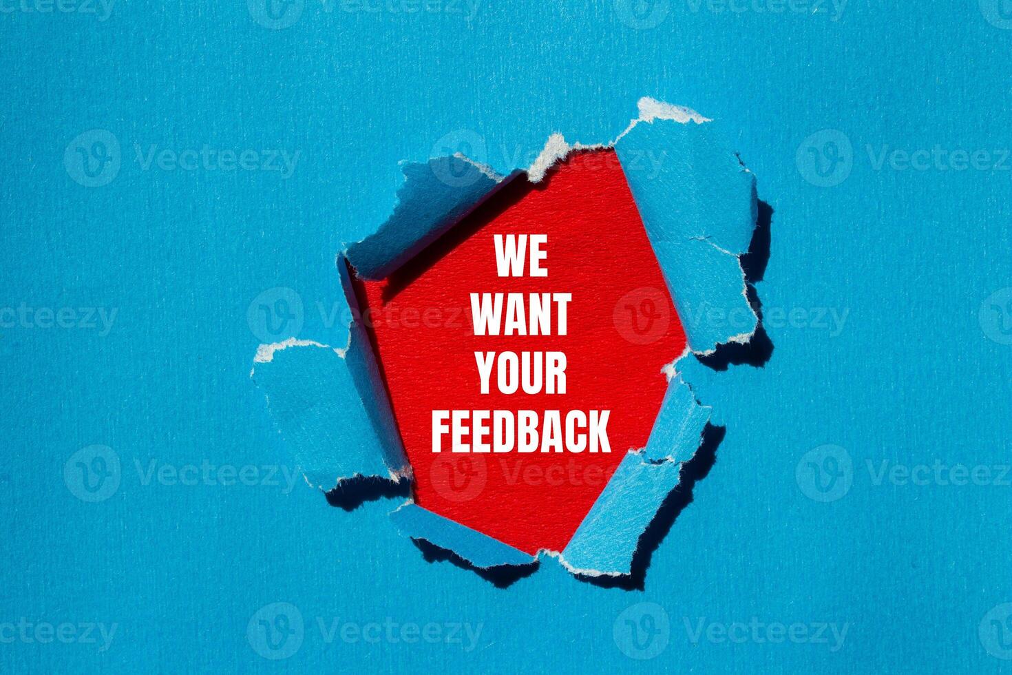 We want your feedback message written on ripped torn blue paper with red background. Conceptual we want your feedback symbol. Copy space. photo