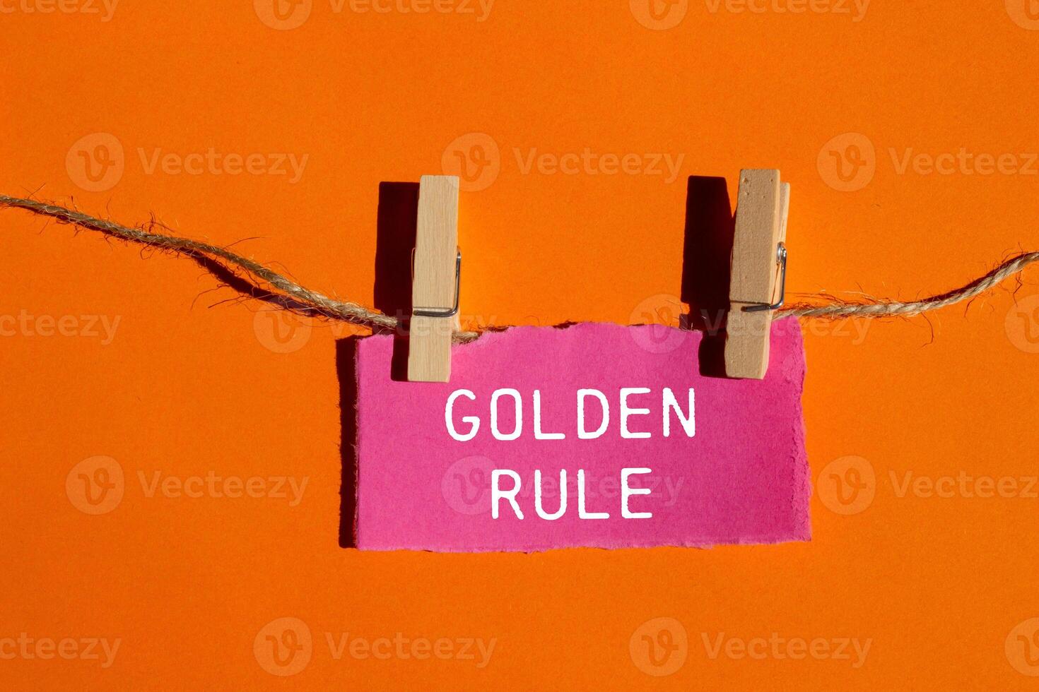 Golden rule message written on ripped torn pink paper piece with orange background. Conceptual golden rule symbol. Copy space. photo