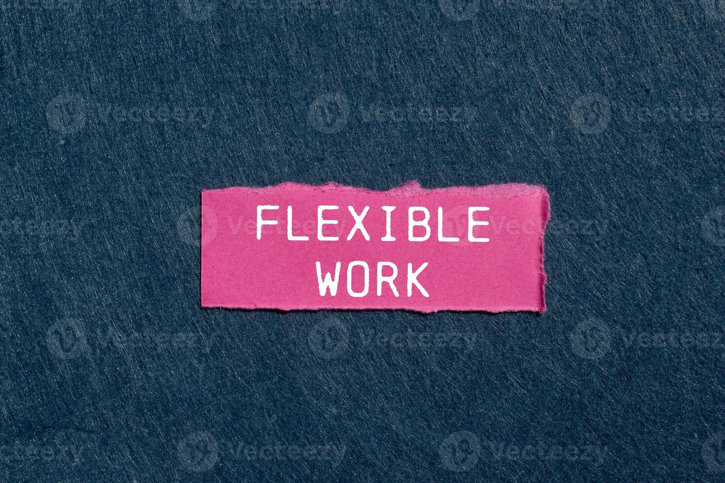Flexible work message written on ripped pink torn paper piece on gray background. Conceptual flexible work symbol. Copy space. photo