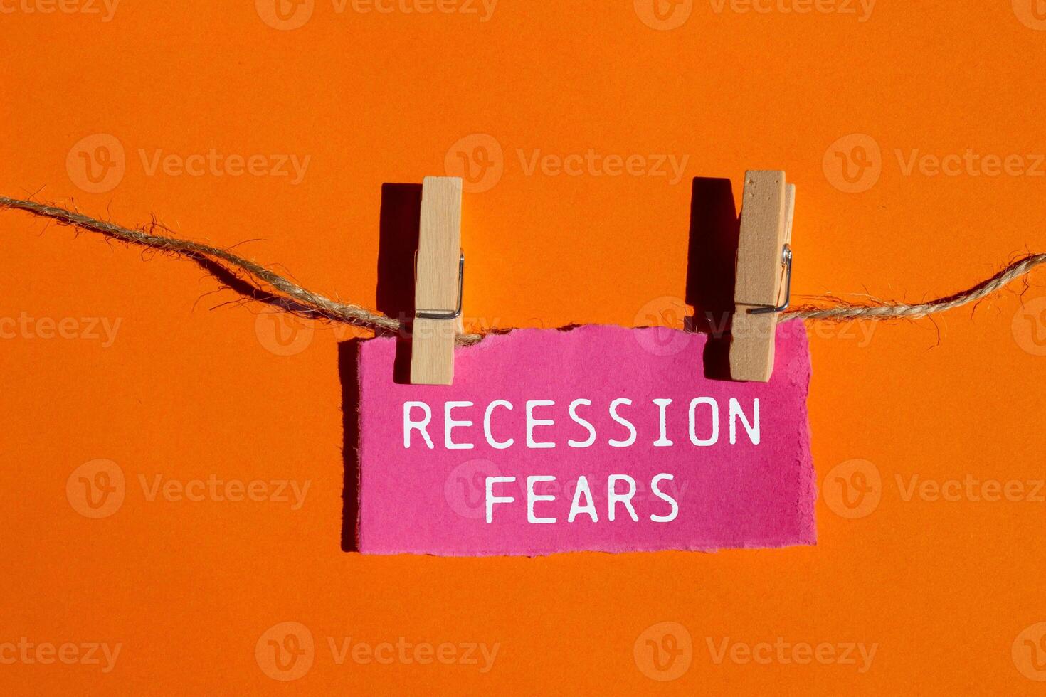 Recession fears message written on ripped pink torn paper piece on orange background. Conceptual recession fears symbol. Copy space. photo