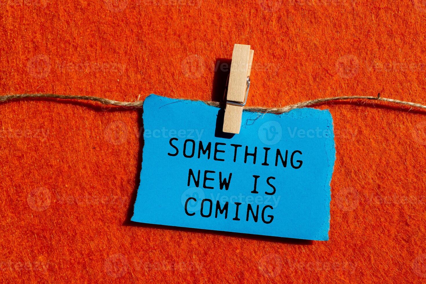 Something new is coming message written on ripped blue torn paper piece on orange background. Conceptual something new is coming symbol. Copy space. photo