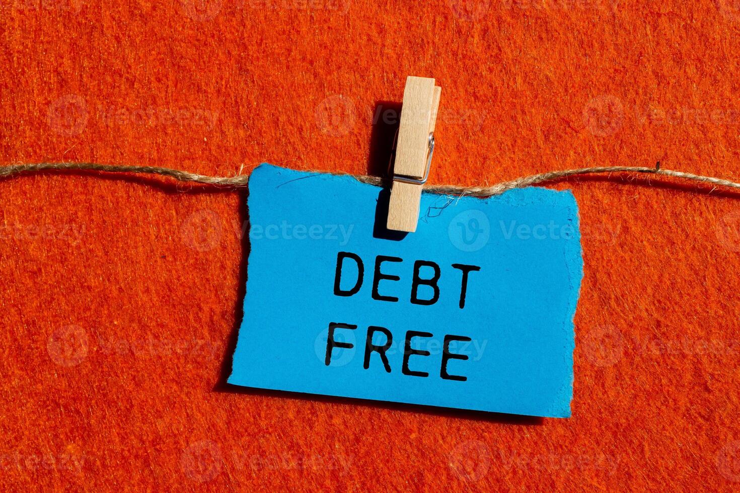 Debt free message written on ripped blue torn paper piece on orange background. Conceptual debt free symbol. Copy space. photo