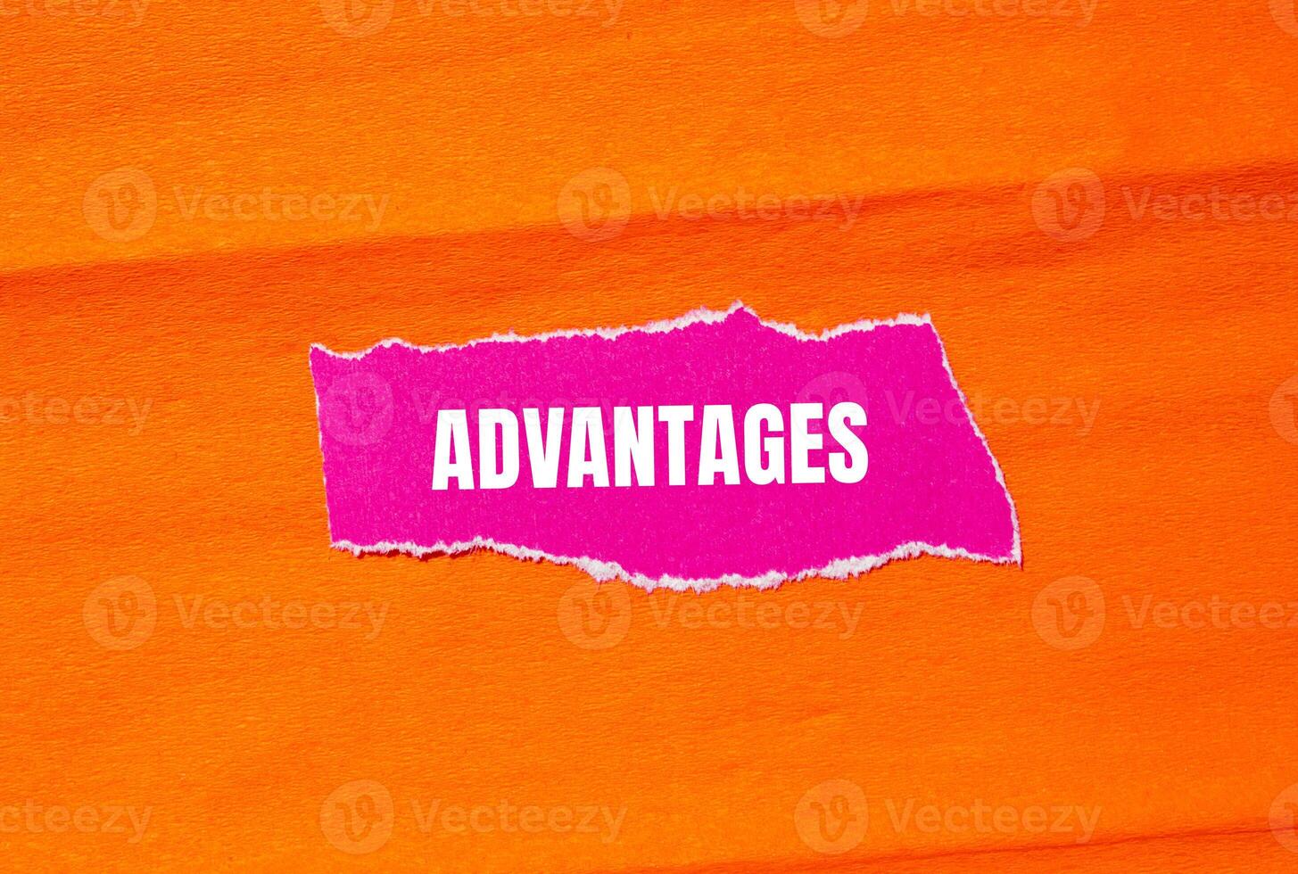 Advantages message written on ripped torn pink paper with orange background. Conceptual advantages symbol. Copy space. photo