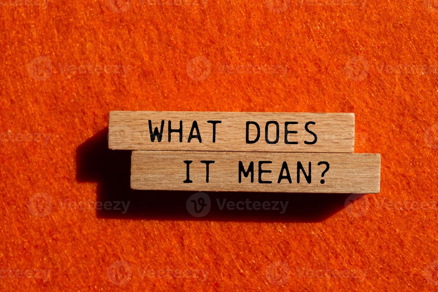 What does it mean question written on wooden blocks on orange felt background. Conceptual what does it mean question symbol. Copy space. photo