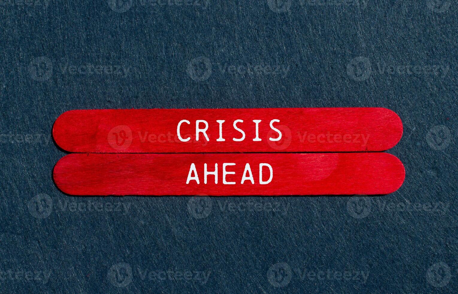 Crisis ahead message written on red wooden sticks on gray felt background. Conceptual crisis ahead symbol. Copy space. photo