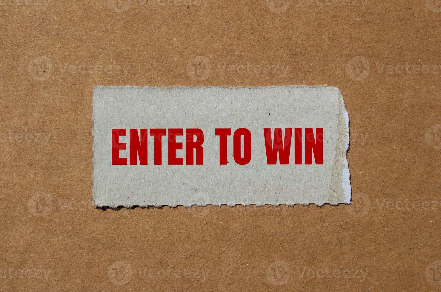 Enter to win message written on ripped torn paper piece with cardboard background. Conceptual enter to win symbol. Copy space. photo