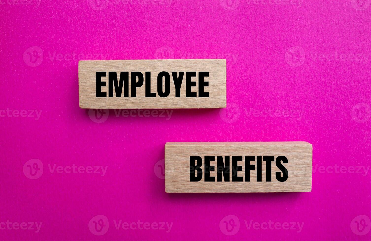 Employee benefits message written on wooden blocks with pink background. Conceptual employee benefits symbol. Copy space. photo