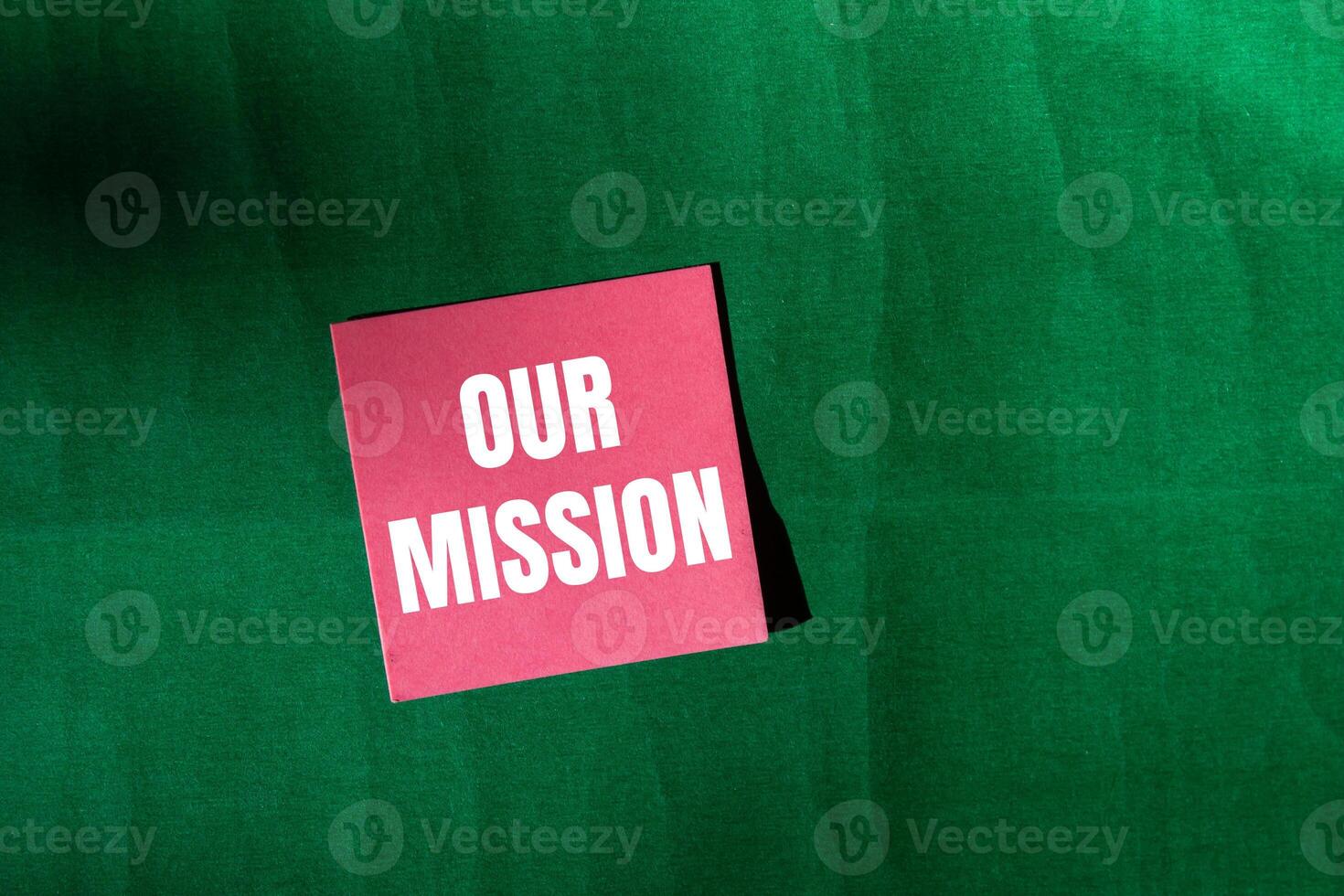 Our mission message written on pink paper with green background. Conceptual our mission symbol. Copy space. photo