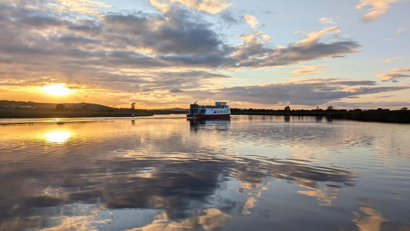 Corrib princes touristic boat cruise on Corrib river at sunset with sky reflection in water, nature background, Galway, Ireland photo