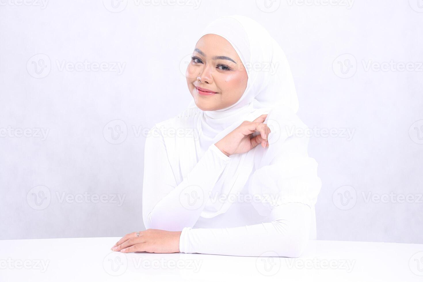 The charm of a smiling veiled woman with perfect and healthy radiant white skin, hands on the table and left arm isolated on a white background. Closeup of a face with makeup for skincare, health photo