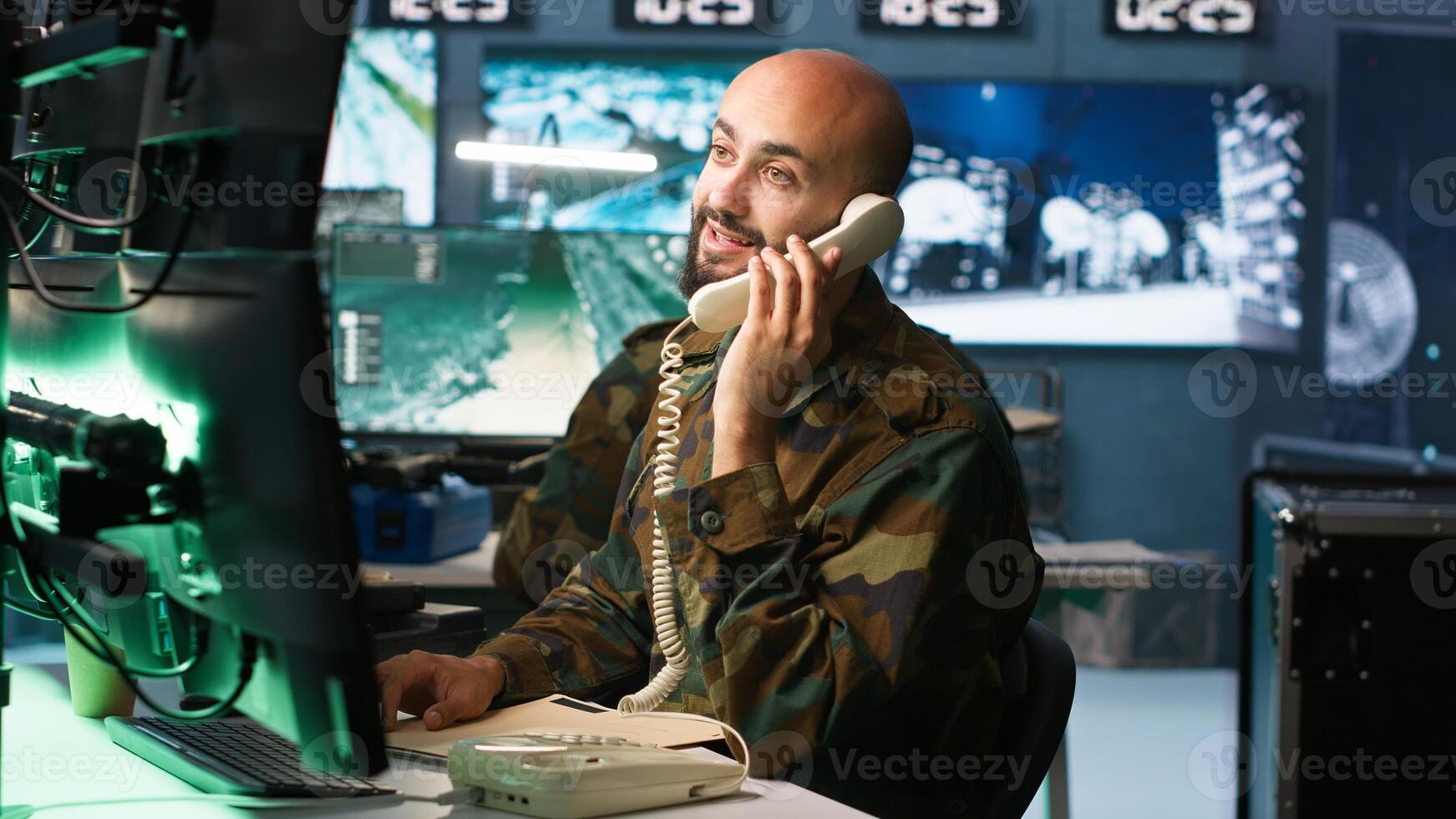 Military officer in command post receiving telephone call while looking at intel files. Intelligence specialist reading opponents strategy mission case file and talking on phone, camera A photo