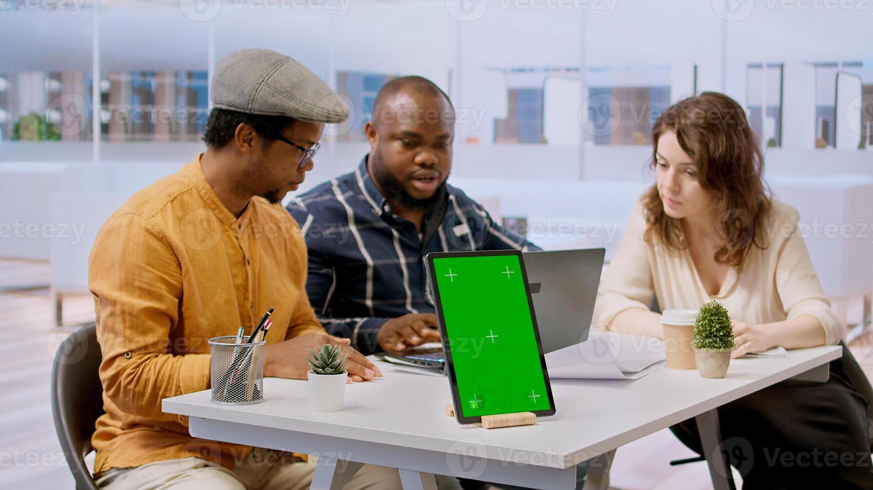 Clients discussing with the contractor next to green screen on tablet, meeting to review blueprints for a new office space. Business people looking to invest in real estate with realtor. Camera A. photo
