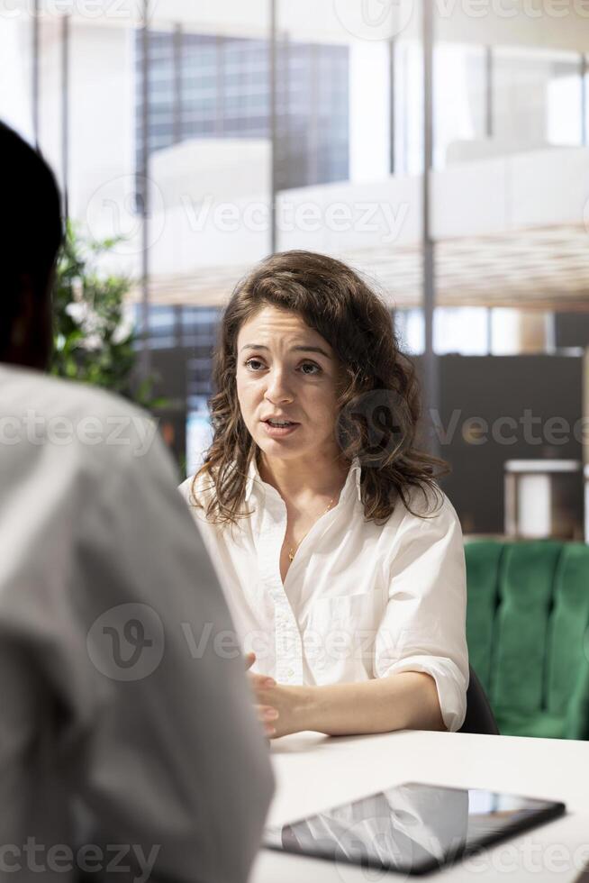 Motivated job interview candidate interested in career advancement, talking with HR specialist. Applicant discussing with recruiter, wishing to get hired for top level job photo