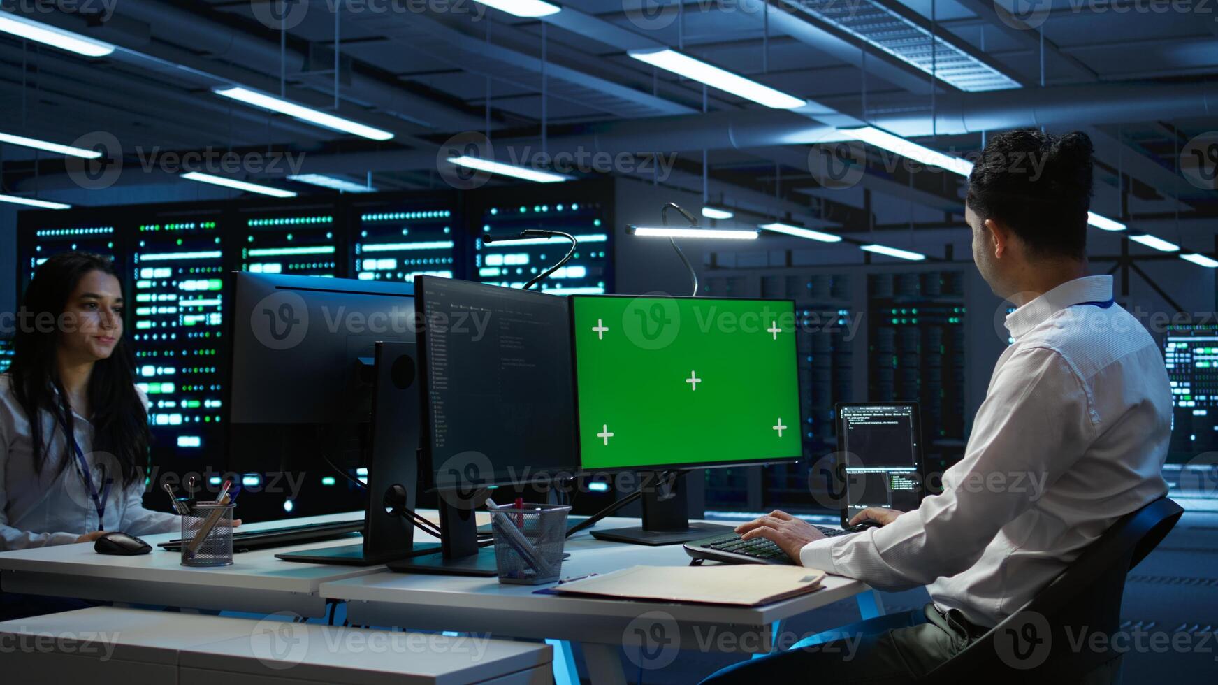 Programmer in data center managing and maintaining databases using mockup PC, ensuring data integrity and security. Expert updating server room systems using green screen computer, camera B photo