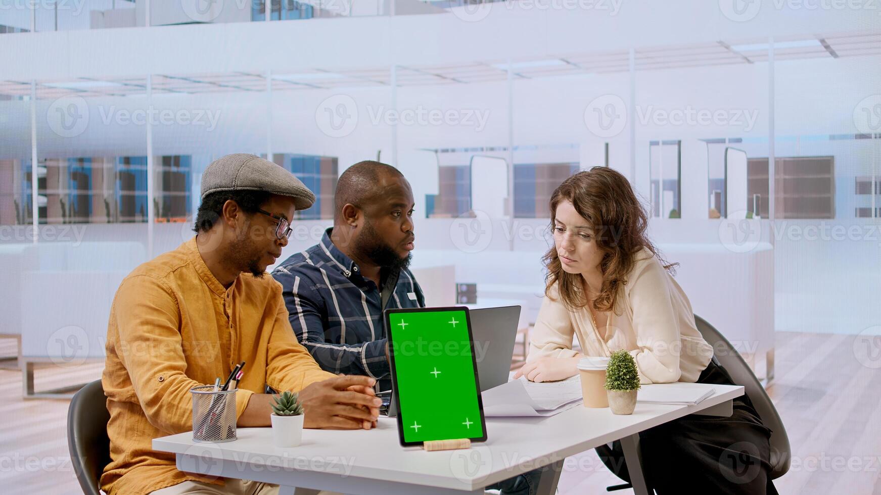 Businessman discussing with the real estate agents next to chroma key on tablet, meeting to negotiate leasing contract terms before looking at blueprints for an office relocation. Camera A. photo