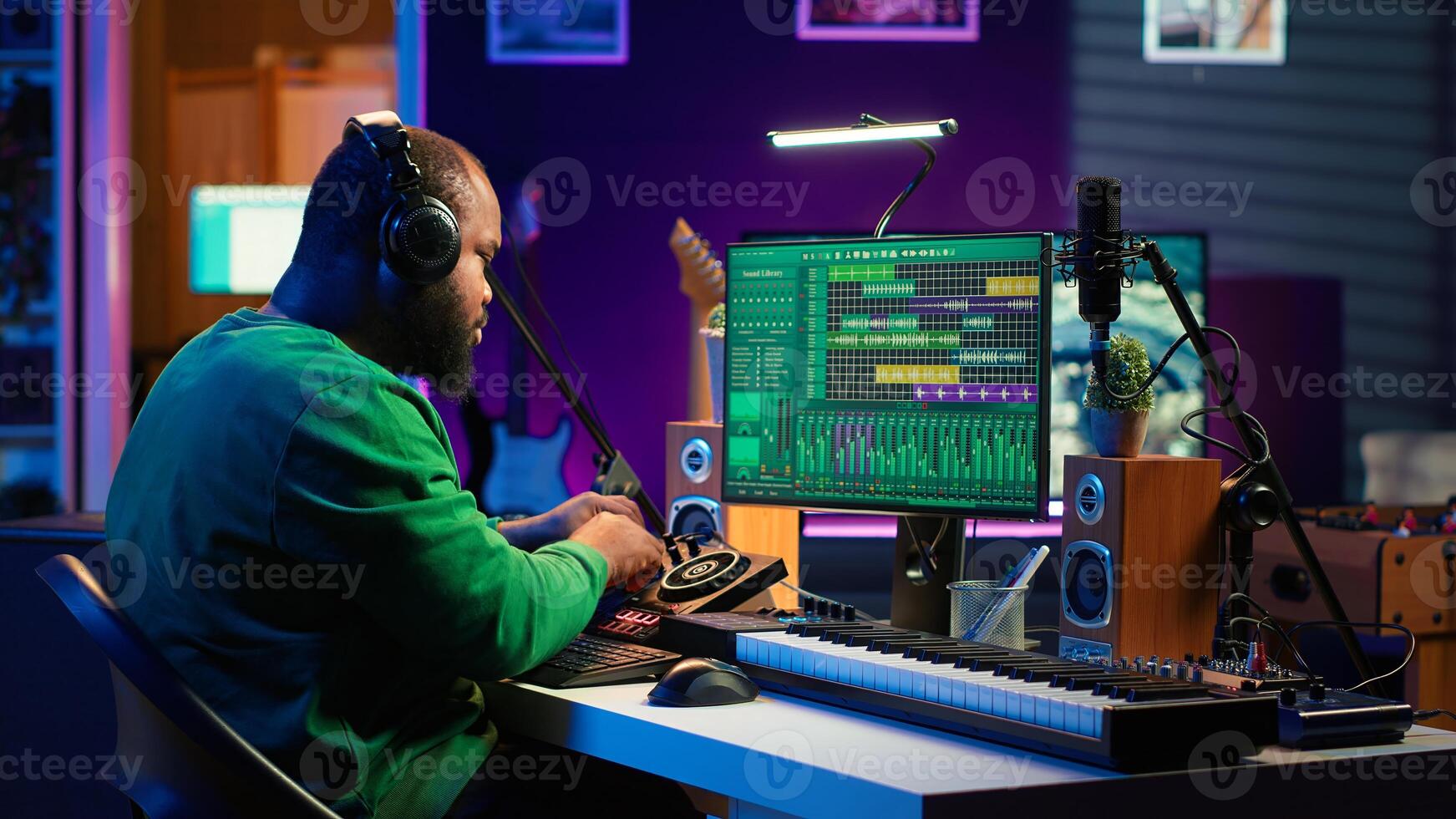 Confident music composer mixing sounds on digital audio software, creating a cool atmosphere in his home studio. Young cheerful producer composing new soundtracks with stereo gear. Camera A. photo