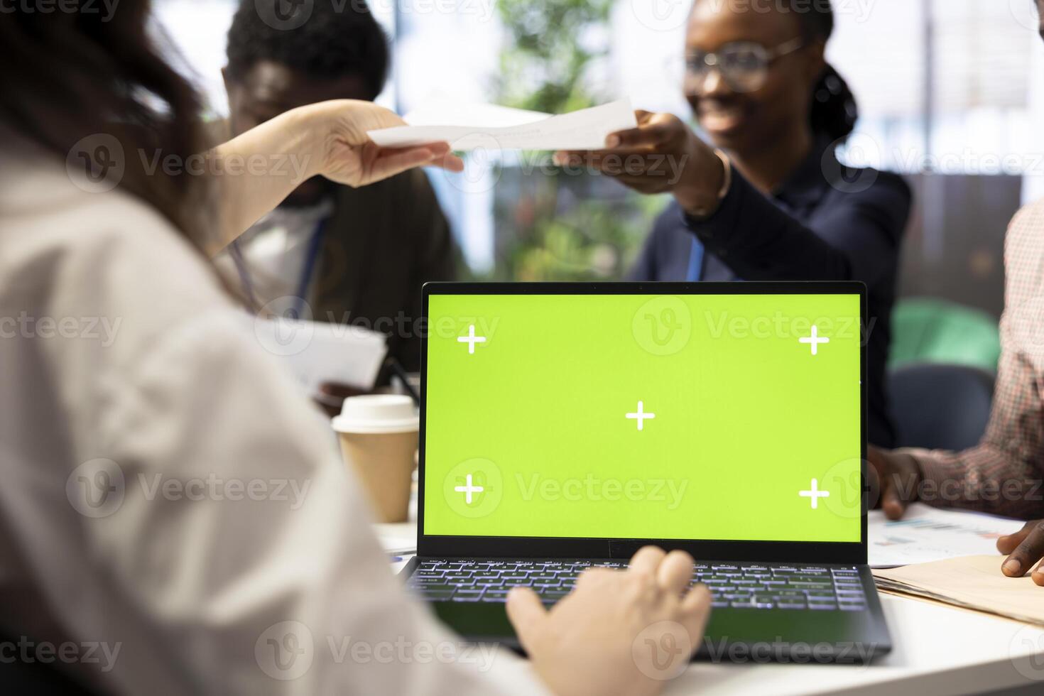 CEO uses laptop with green screen during a meeting with business associates, reviewing project development progress. Utilizing detailed analytics and mockup to ensure strategic objectives. photo