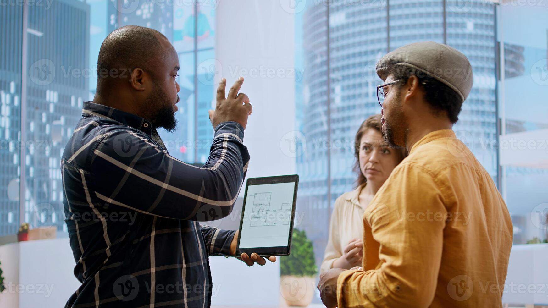 Real estate investment expert and entrepreneur planning an office space relocation, examining blueprints and discussing the layout for the new workspace. Looking to buy urban property. Camera A. photo