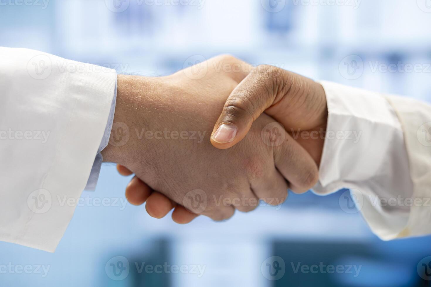 Diverse medics shaking hands after a successful treatment plan collaboration during a meeting with licensed physicians. Doctors with expertise doing a handshake for great partnership. Close up. photo