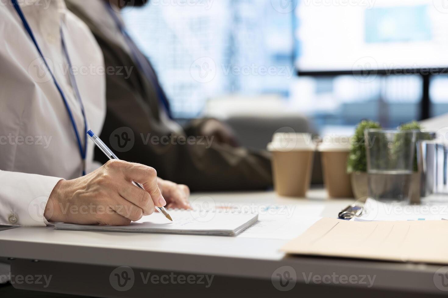 Financial consultant takes notes during a project briefing meeting, working on allocating available resources to meet the business objectives. Expert making future projections. Close up. photo