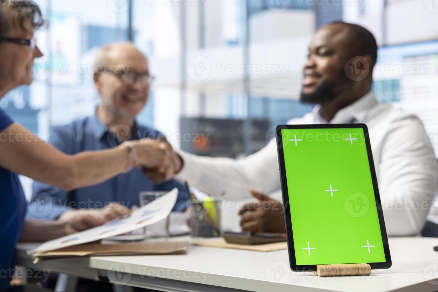 Financial advisor shakes hands with old people after choosing a retirement plan to secure their pension, tablet with green screen. Banker talking to elderly couple about life insurance. photo