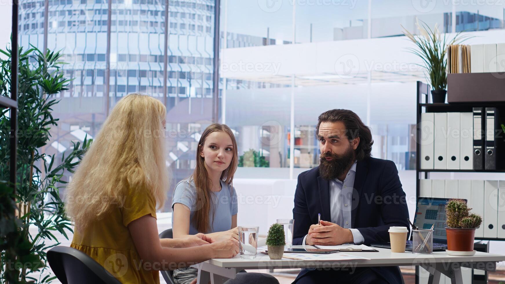 Financial advisor developing and presenting financial strategies and plans to customers. Consultant in office assisting clients with investment portfolio management, camera B photo