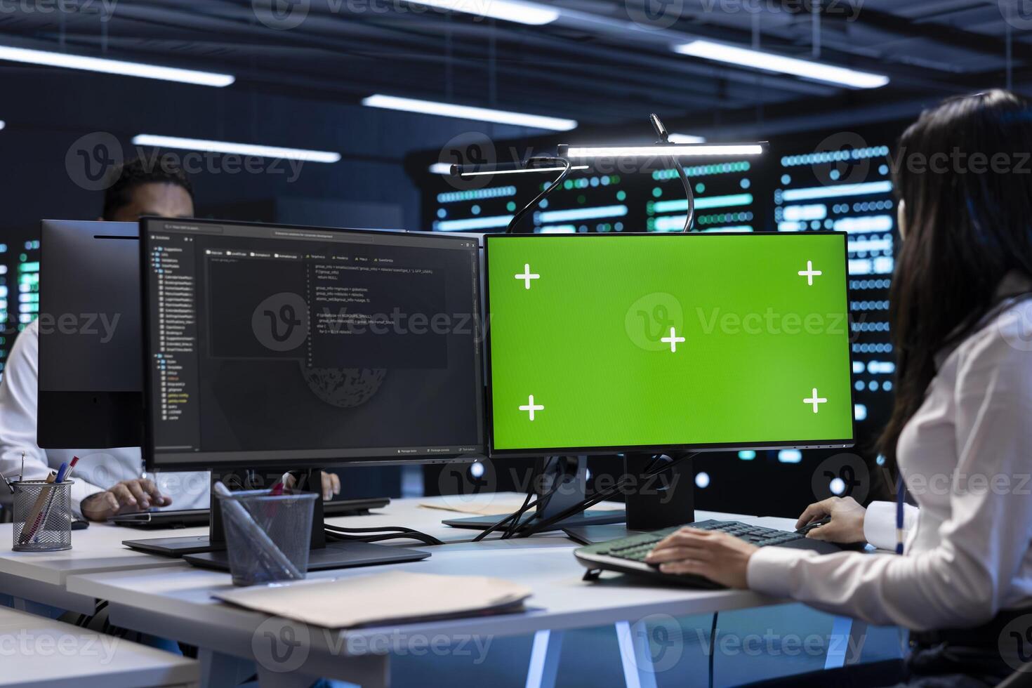 Engineer working on green screen PC in data center housing thousands of servers, storage devices, and networking components, providing vast amounts of computing resources photo