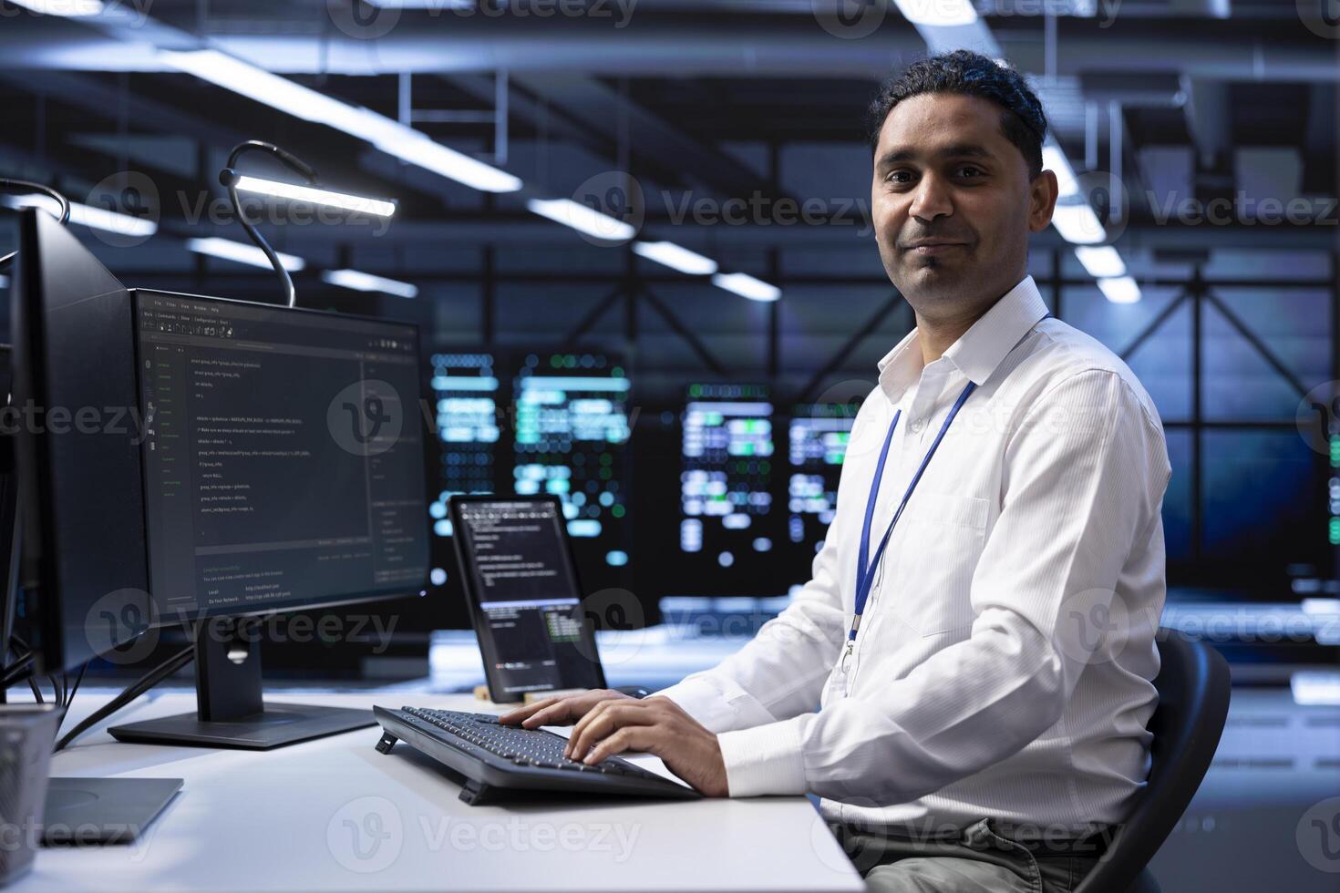 Portrait of smiling engineer checking event logs on computer to find out of order data center electronics root cause. Happy technician using PC to review blade servers system settings photo