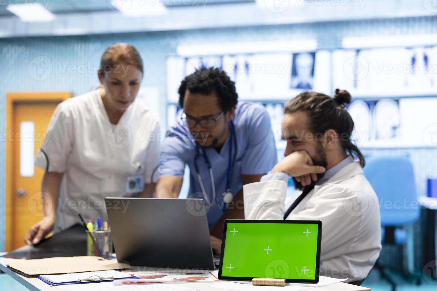 Group of doctors consulting hospital records next to chroma key display, using x ray test results to examine the diagnosis. Diverse experts meeting at private clinic to provide a treatment plan. photo
