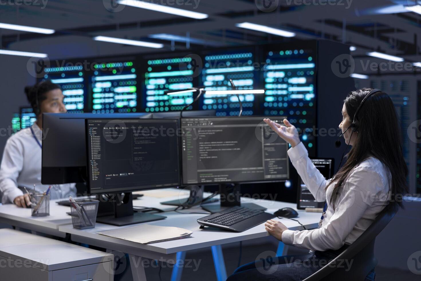 Data center workers in remote call, providing customer support, troubleshooting damages. Coworkers in server hub carrying out operational interventions requested by clients, using microphone photo