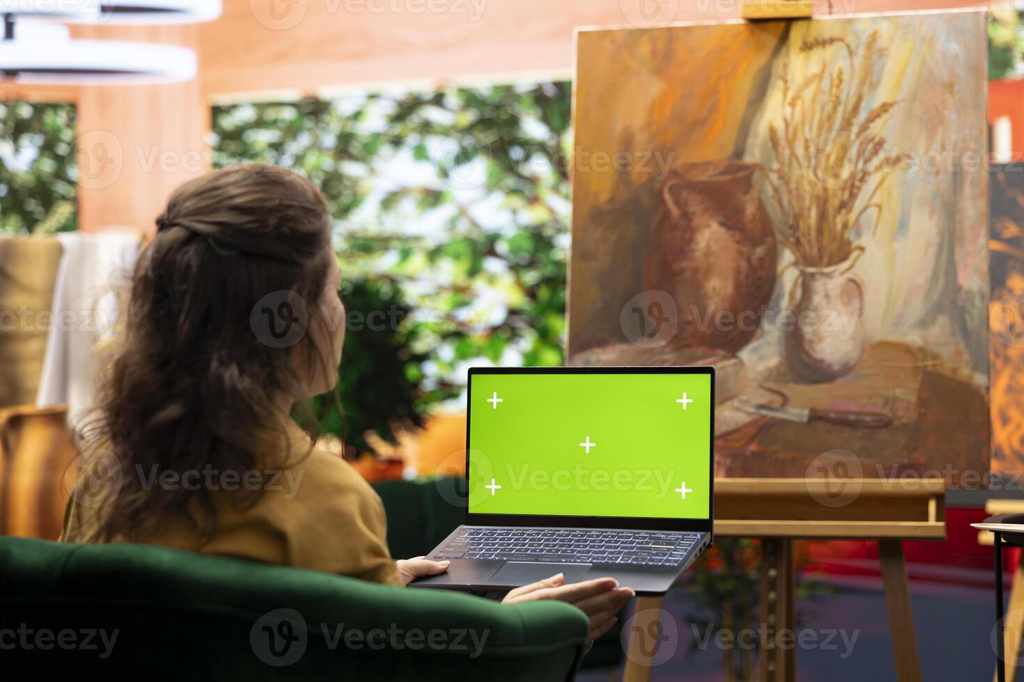 Skilled artist using a chroma key mockup on display in art and craft workshop, working on her multicolored masterpiece for her gallery exhibition. Proud confident woman admires her painting. photo