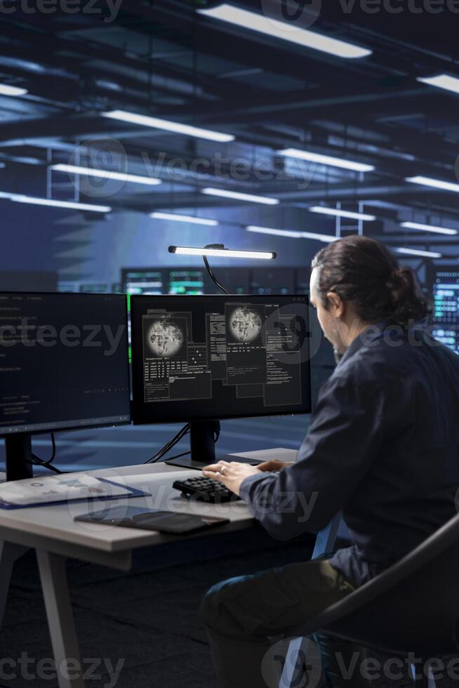Technician working in data center overseeing international user traffic on computer. IT worker in server room facility hosting websites and delivering web content to online customers photo
