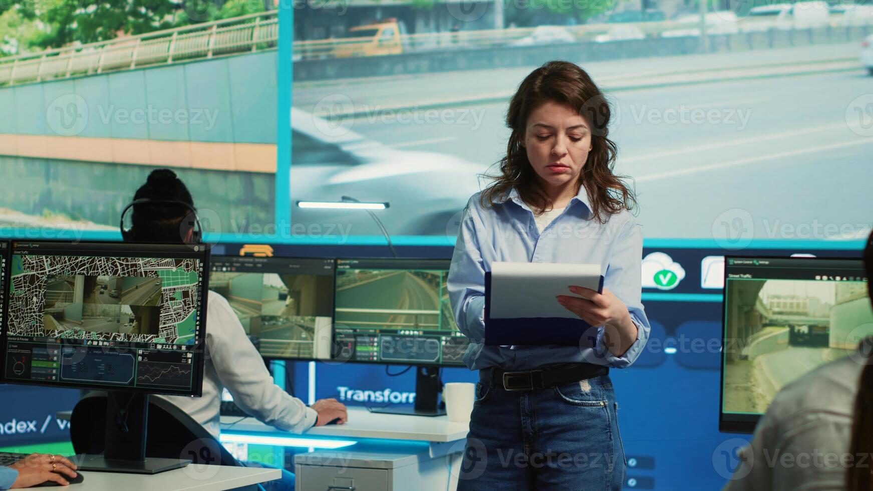 Portrait of woman supervisor overseeing the traffic surveillance monitoring activity in a observation room, CCTV satellite system. Diverse team of people handling license plate reading. Camera A. photo