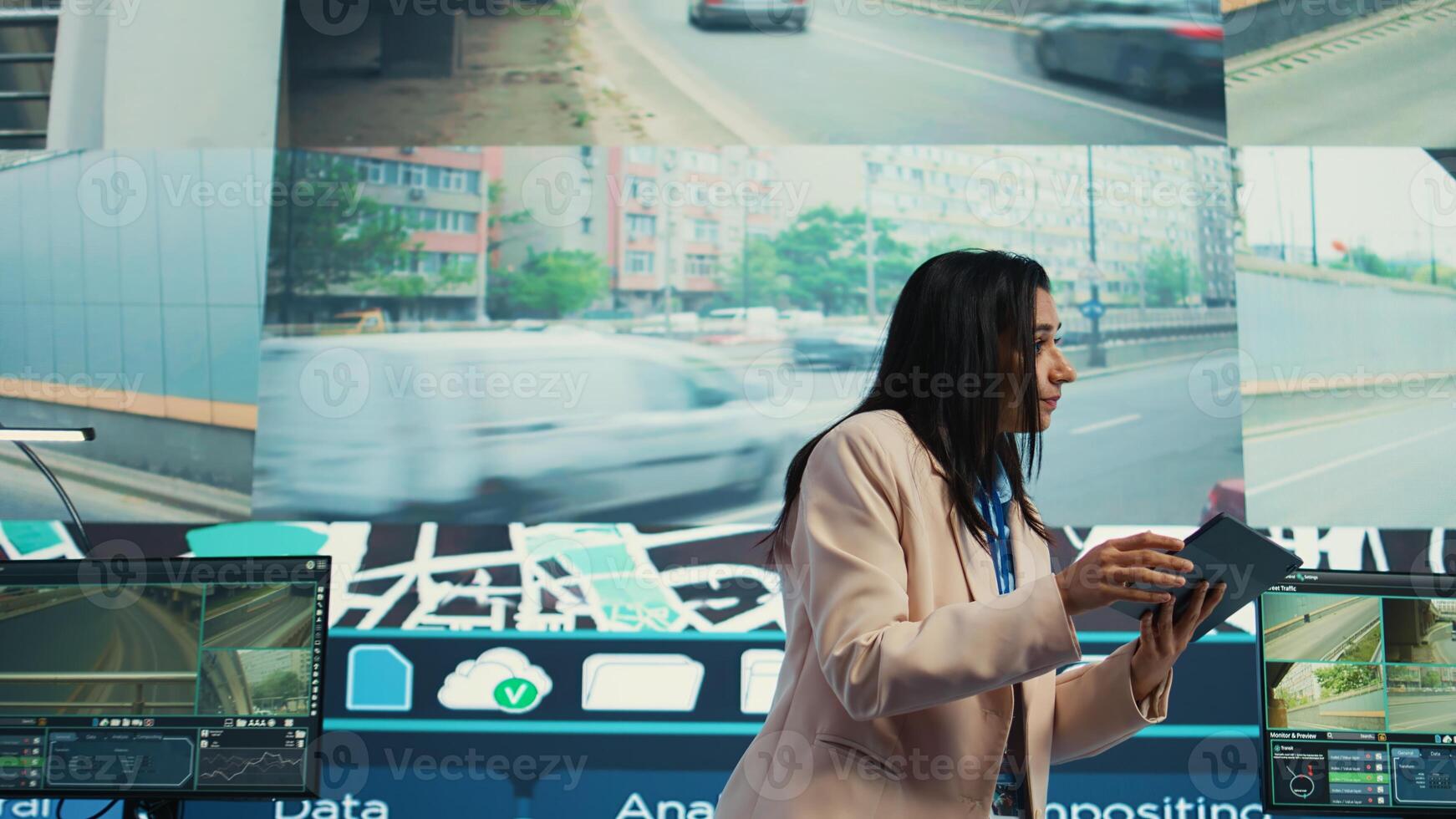 Indian supervisor gather intelligence on cargo delivery logistics by following the route through street traffic via satellite map. Manager works with her team in control center. Camera B. photo