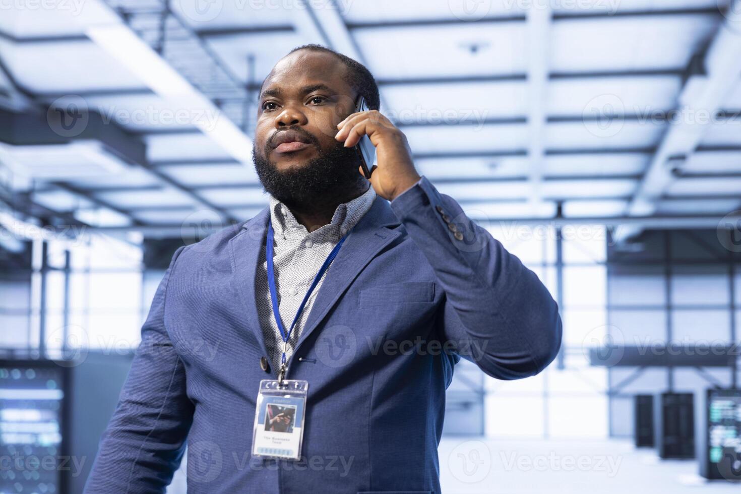 Supervisor discussing on mobile phone in high tech data center housing advanced computing hardware. Professional delegating tasks in futuristic server farm during telephone call photo