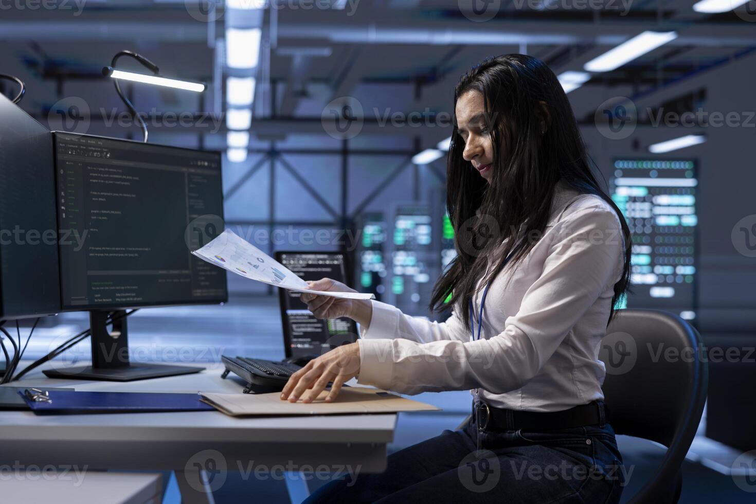 Technician maintaining accurate documentation of data center equipment, configurations, and procedures. Woman in server hub establishing performance benchmarks and conducting analysis photo