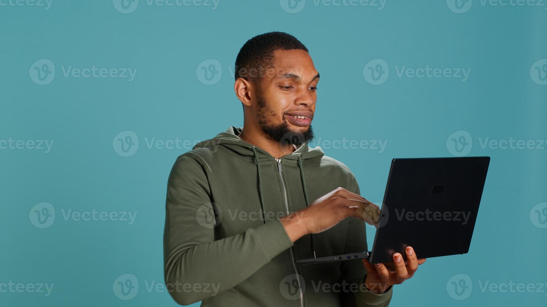 Happy man adding payment method on website using laptop, delighted to take advantage of promotions, studio background. Person thrilled to do internet shopping, typing credit card data, camera A photo