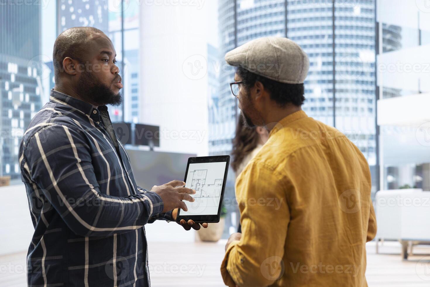 Real estate agent presenting a new office building to clients, discussing the detailed blueprints using a tablet during the property tour. Potential leasing investment opportunity. photo